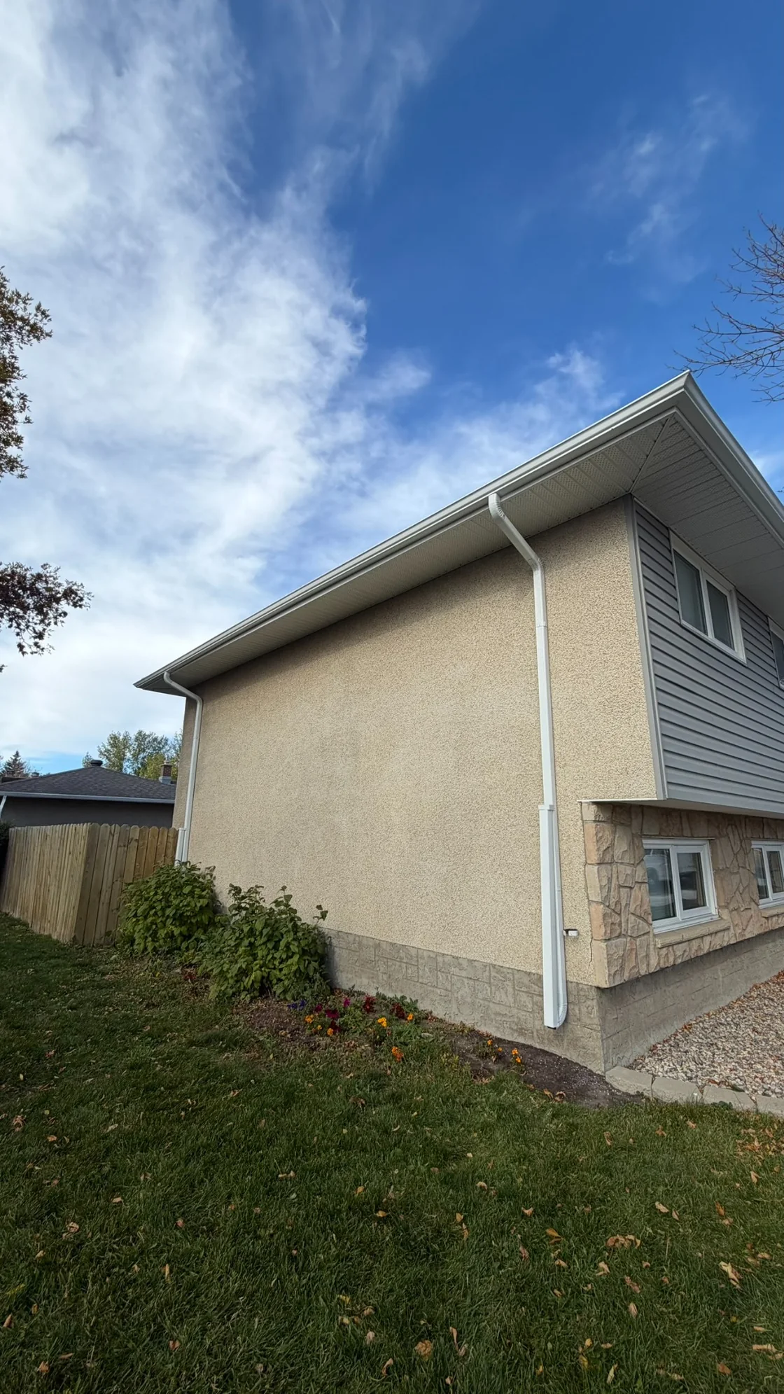 White downspouts running beneath the eaves and along the exterior wall of a Regina home.