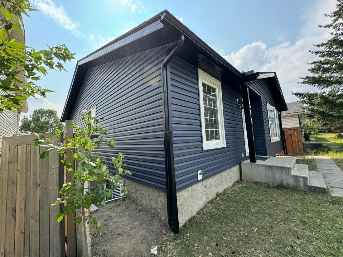 Dark aluminum gutters and downspout along a home with dark siding